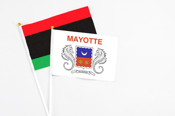 Mayotte and Libya stick flags on white background. High quality fabric, miniature national flag. Peaceful global concept.White floor for copy space.