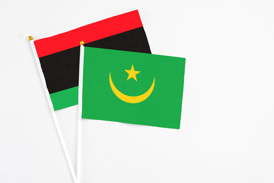 Mauritania and Libya stick flags on white background. High quality fabric, miniature national flag. Peaceful global concept.White floor for copy space.