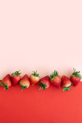 Minimal fresh strawberries on pastel pink and red background