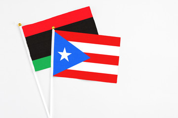 Puerto Rico and Libya stick flags on white background. High quality fabric, miniature national flag. Peaceful global concept.White floor for copy space.