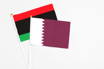 Qatar and Libya stick flags on white background. High quality fabric, miniature national flag. Peaceful global concept.White floor for copy space.