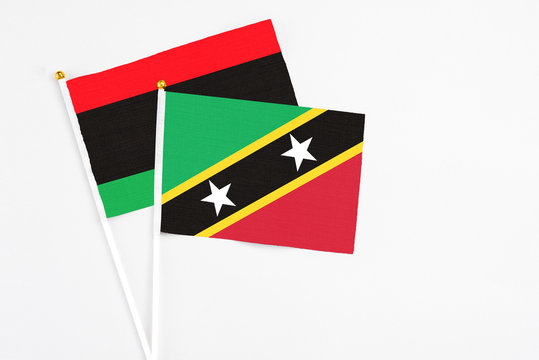 Saint Kitts And Nevis and Libya stick flags on white background. High quality fabric, miniature national flag. Peaceful global concept.White floor for copy space.