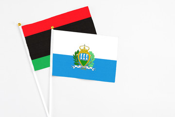 San Marino and Libya stick flags on white background. High quality fabric, miniature national flag. Peaceful global concept.White floor for copy space.