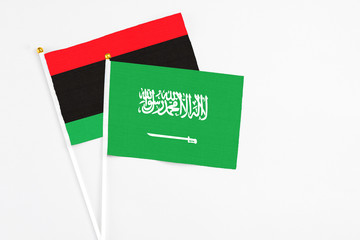 Saudi Arabia and Libya stick flags on white background. High quality fabric, miniature national flag. Peaceful global concept.White floor for copy space.