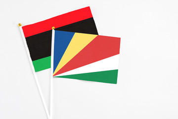 Seychelles and Libya stick flags on white background. High quality fabric, miniature national flag. Peaceful global concept.White floor for copy space.