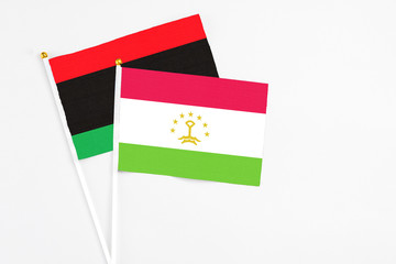 Tajikistan and Libya stick flags on white background. High quality fabric, miniature national flag. Peaceful global concept.White floor for copy space.