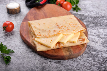 Delicious pancakes with cheese on wooden board, concrete gray stone table background. Top view homemade breakfast. Russian national food. Russian cuisine.