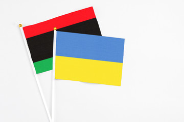 Ukraine and Libya stick flags on white background. High quality fabric, miniature national flag. Peaceful global concept.White floor for copy space.