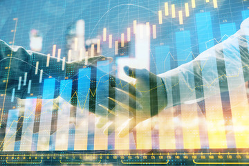 Double exposure of financial chart on cityscape background with two businessmen handshake. Concept of financial analysis and investment opportunities