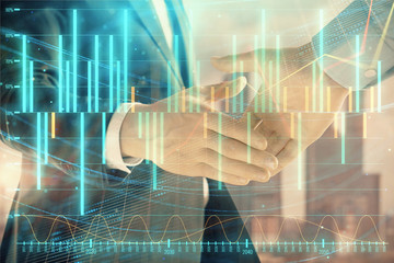 Double exposure of financial graph on cityscape background with two businessman handshake. Concept of stock market deal