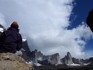 A man climber sitting on a rock and gazing at the majestic mountains, Torres del Paine trekking,...