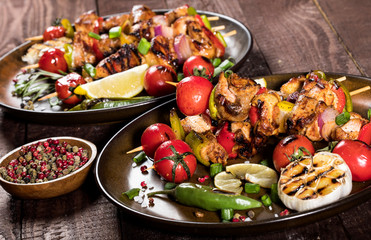 Fototapeta na wymiar Grilled chicken skewers with spices and vegetables in a pans on wooden background