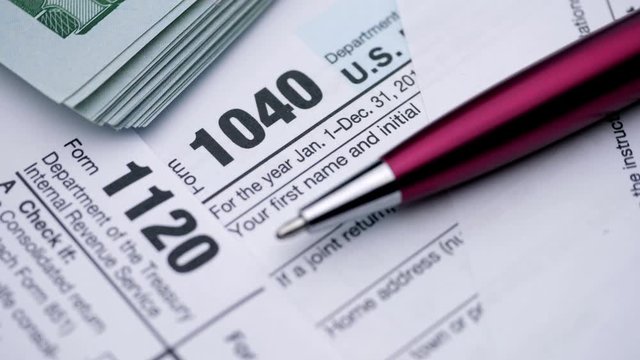  USA tax form 1040, 1120, and dollar bills, close up