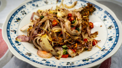 Fermented fried freshwater bream fish with fried onion or ikan pekasam in a plate on table.