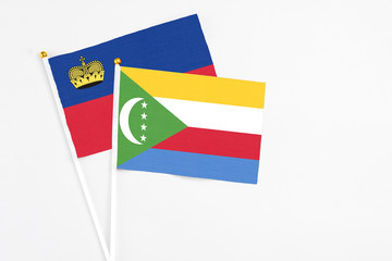 Comoros and Liechtenstein stick flags on white background. High quality fabric, miniature national flag. Peaceful global concept.White floor for copy space.