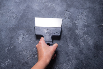 Hand with  putty knifes on grey background
