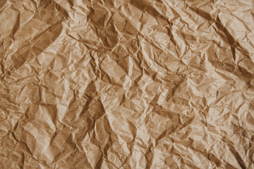 Wrinkled kraft brown paper as a background image. Coarse grain, crumpled, grunge texture detail