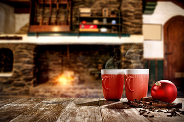 Christmas mugs with a hot drink. Steam smoke and Christmas decoration. Blurry background of a rustic fireplace with flame. American rifles on a stand. Place for your christmas gifts.Dark mood shadows.