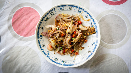 Fermented fried freshwater bream fish with fried onion or ikan pekasam in a plate on table.