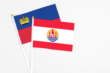 French Polynesia and Liechtenstein stick flags on white background. High quality fabric, miniature national flag. Peaceful global concept.White floor for copy space.