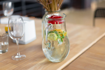 Healthy food and drinks. Water in glass mug with lemon and mint on wooden table in cafe