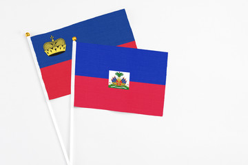 Haiti and Liechtenstein stick flags on white background. High quality fabric, miniature national flag. Peaceful global concept.White floor for copy space.