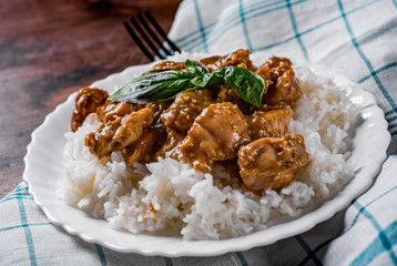 Chicken Breast with sauce and Rice in white plate on a wooden table background