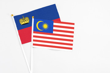 Malaysia and Liechtenstein stick flags on white background. High quality fabric, miniature national flag. Peaceful global concept.White floor for copy space.