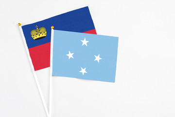 Micronesia and Liechtenstein stick flags on white background. High quality fabric, miniature national flag. Peaceful global concept.White floor for copy space.