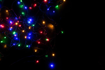 Dark room, multicolored garlands are burning. Top view. Christmas background