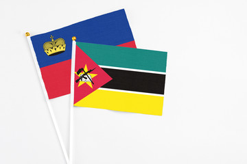 Mozambique and Liechtenstein stick flags on white background. High quality fabric, miniature national flag. Peaceful global concept.White floor for copy space.