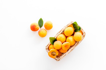 Fresh raw apricots in basket on white background top view copy space, pattern with leaves