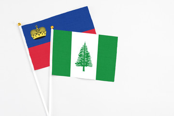 Norfolk Island and Liechtenstein stick flags on white background. High quality fabric, miniature national flag. Peaceful global concept.White floor for copy space.