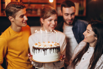 cheerful young company celebrates birthday and have a cake with candles