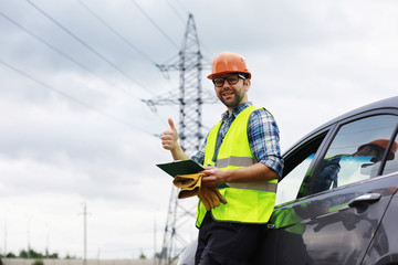 A man in a helmet and uniform, an electrician in the field. Professional electrician engineer...