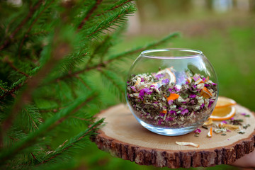 Therapeutic herbal collection of dried herbs. Medicinal collection in a transparent glass vase on a background of green forest, background in blur with bokeh. 