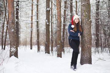 Fototapeta na wymiar A young girl in a winter park on a walk. Christmas holidays in the winter forest. The girl enjoys winter in the park.