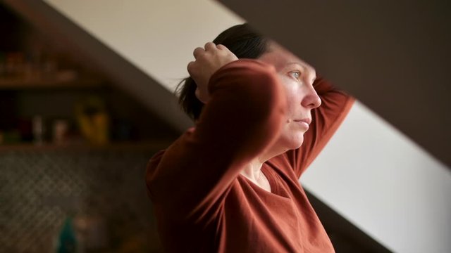 Depressed woman standing by the loft window felling sad