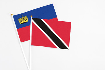 Trinidad And Tobago and Liechtenstein stick flags on white background. High quality fabric, miniature national flag. Peaceful global concept.White floor for copy space.