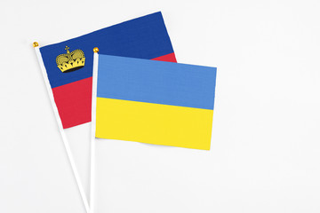 Ukraine and Liechtenstein stick flags on white background. High quality fabric, miniature national flag. Peaceful global concept.White floor for copy space.