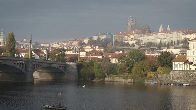 View of Prague from the river. Old Prague, view of the city in the early autumn morning. A fisherman on a boat on a rik in a stradom garden in Europe.