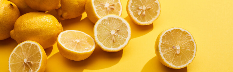 ripe cut and whole lemons on yellow background, panoramic shot