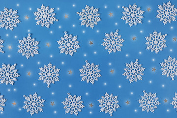 Christmas pattern with snowflakes, stars and sparkling lights on a blue canvas background.
