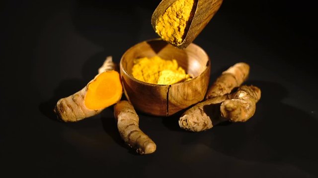 Turmeric curcuma powder falls in a bowl drom scoop - Slow motion