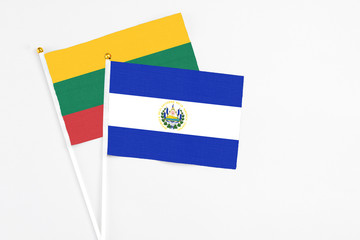El Salvador and Lithuania stick flags on white background. High quality fabric, miniature national flag. Peaceful global concept.White floor for copy space.