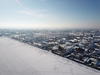 ville sous épais manteau de neige, ambiance hiver de noël, plein de maison en bord de champ par temps ensoleillé et ciel bleu vue aérienne