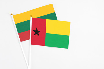 Guinea Bissau and Lithuania stick flags on white background. High quality fabric, miniature national flag. Peaceful global concept.White floor for copy space.