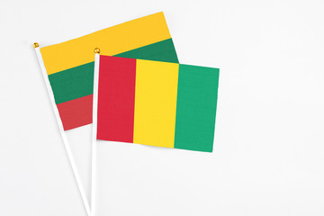 Fototapeta premium Guinea and Lithuania stick flags on white background. High quality fabric, miniature national flag. Peaceful global concept.White floor for copy space.