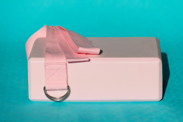 Yoga accessories. A pink cube and yoga strap lie on a blue rug.