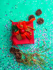 Red gift box with Christmas branch in trendy mint green colors tones. Flat lay background. Festive...